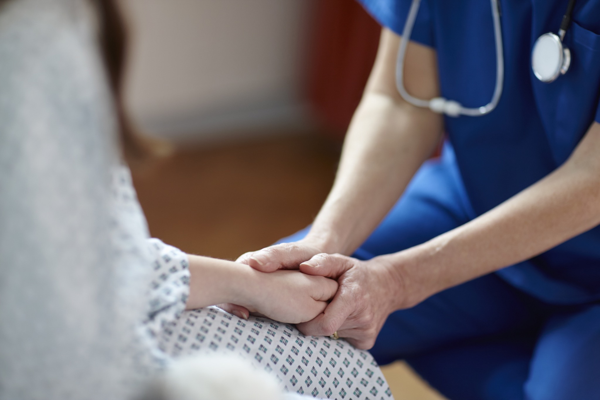 Nurse reassuring a patient by holding her hand after a breast biopsy